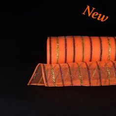 three rolls of orange fabric with gold sequins on them and the word new written in large letters