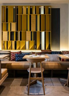 a room with couches, tables and chairs in front of a wall made out of bookshelves