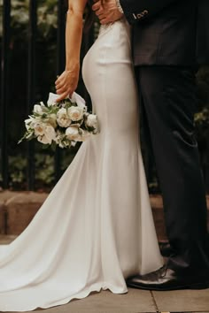 a bride and groom standing together in front of an iron gate at their wedding ceremony