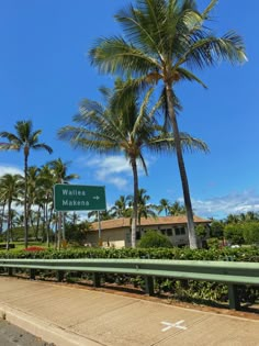 a street sign on the side of a road with palm trees