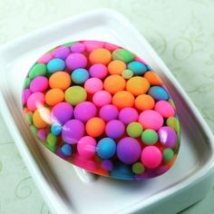 there is a colorful cake on a white plate with pink, green, blue and yellow balls