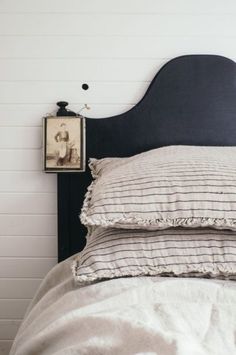 a bed with two pillows on top of it and a framed picture above the headboard