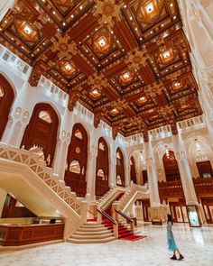 a woman is walking down the stairs in an ornate building