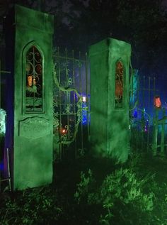 an outdoor cemetery is lit up at night with green lights and decorations on the sides