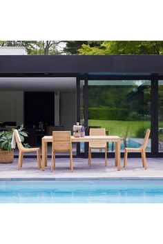 an outdoor table and chairs next to a pool in front of a large glass door