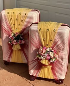 two pieces of luggage are decorated with flowers and ribbons on the front, side by side