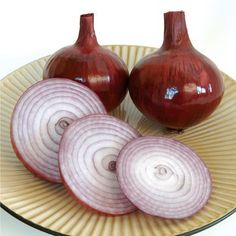 three onions on a plate with one onion cut in half