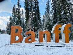 two people standing in front of the word banff on top of snow covered ground