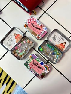 four tins filled with candy sitting on top of a tiled floor