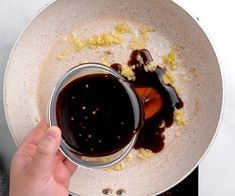 someone is pouring sauce on top of food in a bowl