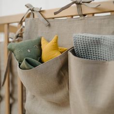 two stuffed animals sit in the pocket of a crib with linens on it