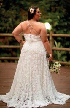 a woman in a white dress is standing on a wooden bridge with her back to the camera