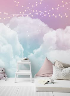 there is a wall mural in the room with clouds and stars on it, as well as a teddy bear