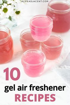 four jars filled with pink gel sitting on top of a white table next to flowers