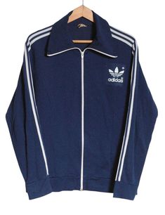 Vintage 1970's Adidas Europa track jacket in a blue colour. Trademark three stripes down the sleeves with large trefoil on the chest. Elasticated waist and cuffs. Made in Hong Kong from a cotton nylon blend. Label reads 7. Condition: Excellent vintage condition. Chest: 40in Length: 26in Inside sleeve: 20in More vintage clothing on our website www.brickvintage.com Adidas Vintage, Vintage Adidas, Blue Colour, Track Jacket, Men's Coats And Jackets, Track Jackets, Adidas Men, Mens Coats, Vintage Clothing