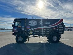 a large truck parked in a parking lot with the sun shining on it's side