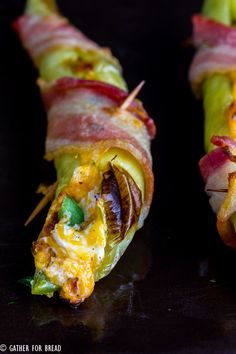 bacon, cheese and other toppings are wrapped up in long strips on a black surface