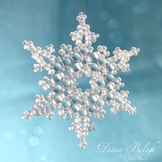 a snowflake ornament hanging from a string on a light blue background