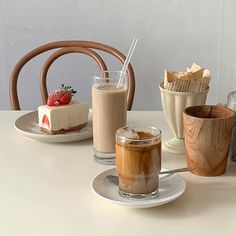 a table topped with two cups filled with liquid and desserts next to each other