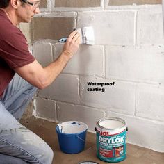 a man is painting a brick wall with white paint