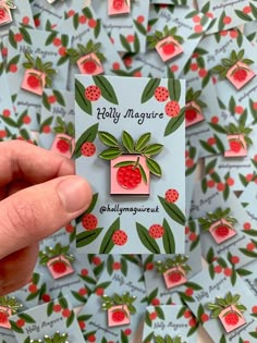 a person holding up a tiny card with strawberries on it in front of many small cards