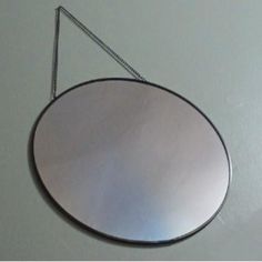 a round mirror hanging on the wall with a chain attached to it's side