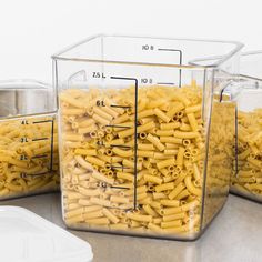 three containers filled with macaroni and cheese sitting on top of a kitchen counter