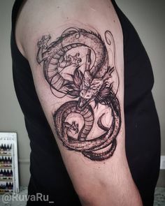 a man with a tattoo on his arm has a dragon and snake in the middle