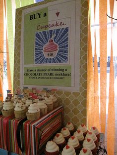 cupcakes are on display in front of a sign