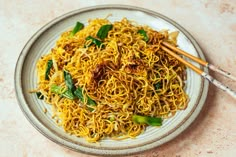 a plate of noodles with chopsticks on the side, ready to be eaten