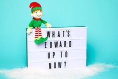 an elf sitting on top of a sign that says what's edward up to now?