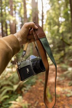 a person holding a camera in the woods