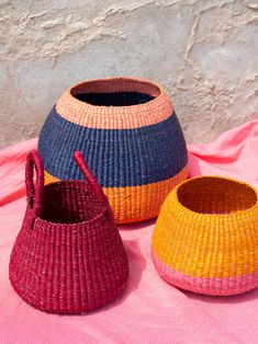 three woven baskets sitting on top of a pink blanket