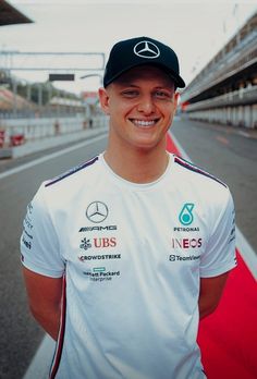 a man standing in front of a race track wearing a white shirt and black hat