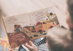 a young child is reading a book on the floor