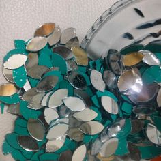 a pile of silver and green mirrors sitting on top of a table