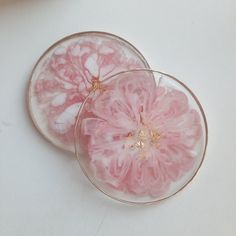 two pink flowers in a glass bowl on a white counter top, one is cut open and the other is partially peeled