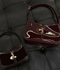 two brown purses sitting on top of a black leather couch next to each other