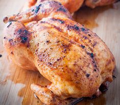 two pieces of chicken sitting on top of a wooden cutting board next to each other