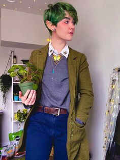 a person with green hair and some plants in their lapel holes, holding a potted plant