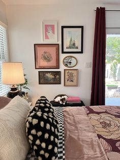 a bed room with a neatly made bed and lots of pictures on the wall above it