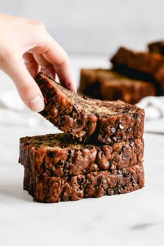 someone is picking up some brownies from the stack on top of another piece of bread