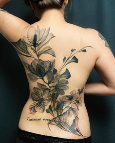 a woman's back tattoo with flowers on it