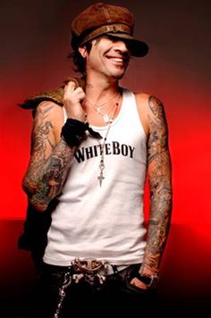 a man with tattoos on his arms and chest wearing a white tank top that says white boy