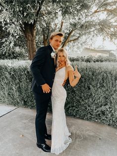 a bride and groom posing for a photo in front of a hedged area at their wedding