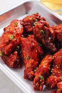 sweet and spicy gochujuang wings with sesame seeds on top in a white serving dish