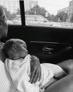 a woman holding a baby in the back seat of a car