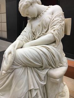 a statue of a woman sitting on top of a white bench