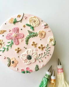 there is a cake decorated with flowers and leaves on the table next to crayons