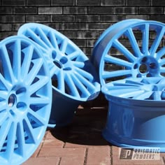 two blue wheels are sitting next to each other on a brick floor in front of a brick wall